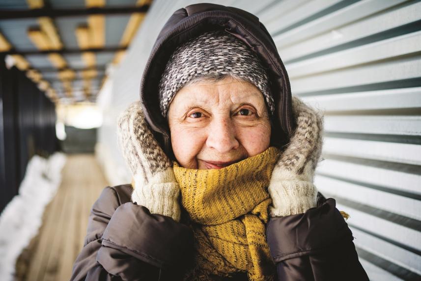 Woman wrapped up in coat, scarf, and mittens.